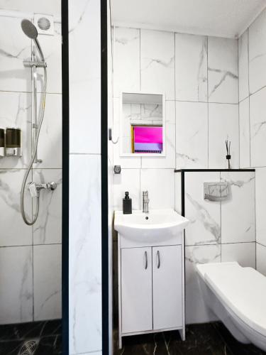 a white bathroom with a sink and a shower at Very Bad Hootel in Kaunas