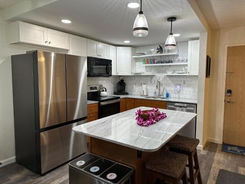 a kitchen with a counter with pink flowers on it at Maui Banyan- Your home away from home on Maui! in Wailea