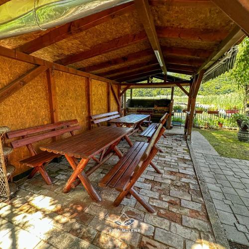 a group of wooden benches sitting under a pavilion at Vila Milena in Međuvršje