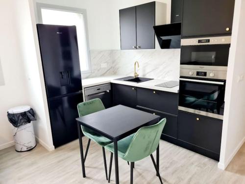 une cuisine avec une table et deux chaises vertes dans l'établissement La Belle Emeraude-Appart cosy proche Paris avec parking, à Alfortville