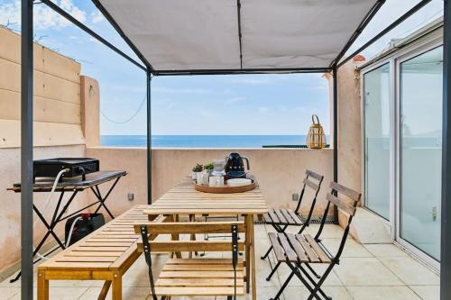 une table et des chaises sur un balcon avec vue sur l'océan dans l'établissement Coquet appartement en bord de mer et corniche, à Marseille