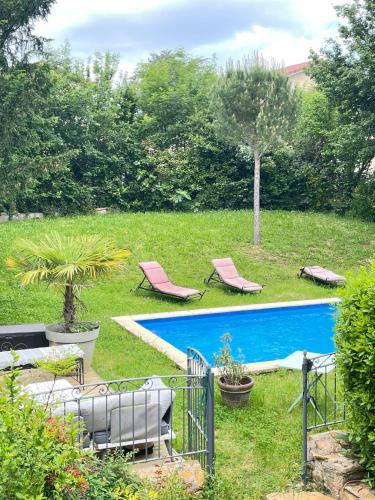 une cour avec deux chaises et une piscine dans l'établissement Chambre rose entre Lyon et Beaujolais - piscine, à Lentilly