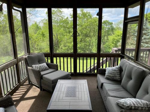 a screened in porch with two chairs and a couch at Secluded 4 bedroom with hot tub minutes from campus in State College