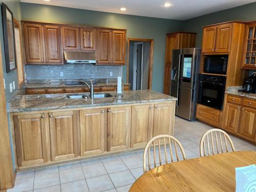 a kitchen with wooden cabinets and a stainless steel refrigerator at Secluded 4 bedroom with hot tub minutes from campus in State College