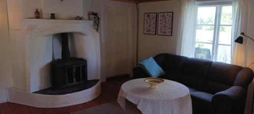 a living room with a black couch and a fireplace at Månsarps skogs- och alpackagård in Vimmerby