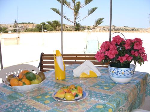 una mesa con un bol de frutas y flores en ella en Case Vacanza Maria, en San Vito lo Capo