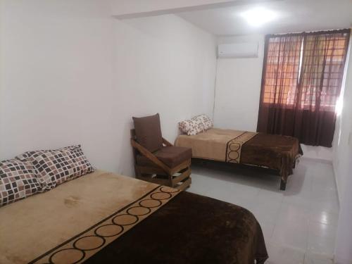 ein Zimmer mit 3 Betten und einem Stuhl darin in der Unterkunft Casa Ixtapa in Ixtapa