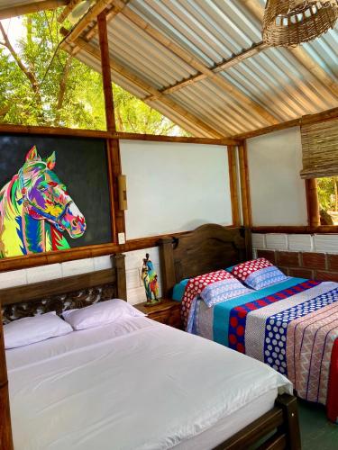 a bedroom with two beds and a painting of a horse at Finca Ecoturistica LOS JAGUEYES in Baraya