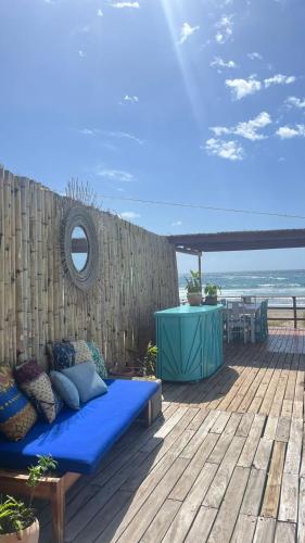a blue couch sitting on a wooden deck with the beach at Lehani Beach Hostel in Praia do Tofo