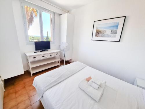 une chambre blanche avec un lit et une télévision dans l'établissement Douceur Marine - T2 avec terrasse, parking, piscine et wifi, à Cavalaire-sur-Mer