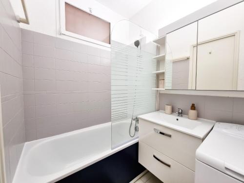 une salle de bain blanche avec un lavabo et une baignoire dans l'établissement Douceur Marine - T2 avec terrasse, parking, piscine et wifi, à Cavalaire-sur-Mer