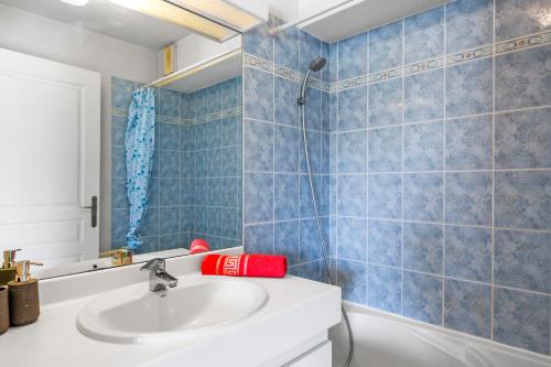 La salle de bains est pourvue d'un lavabo blanc et de carrelage bleu. dans l'établissement Haut Standing /Mandelieu - Cannes, à Mandelieu-la-Napoule