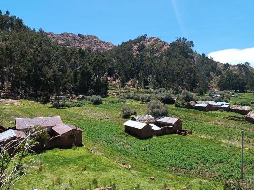 une vieille ferme dans un champ avec des montagnes en arrière-plan dans l'établissement HOTEL ESTANCIA willkawatana LODGE, à Santa Rosa de Yanaque