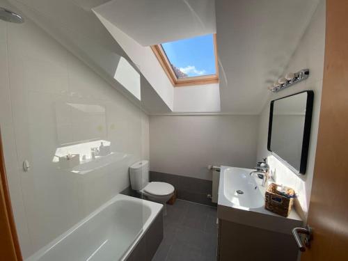 Un baño con lavabo, inodoro y tragaluz. en Ático de Ensueño- Tu Paraíso en Cantabria, en Beranga
