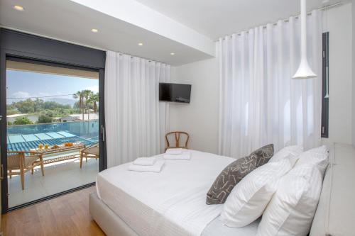 a bedroom with a bed and a balcony with a pool at Aquamarina Villas in Lefkada Town