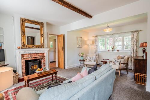 a living room with a blue couch and a fireplace at Beautiful Riverside Cottage with Large Garden, 2BR in Boldre