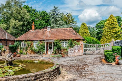 a house with a pond and a fence at Beautiful Riverside Cottage with Large Garden, 2BR in Boldre