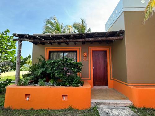 a house with an orange door and plants in front at Cabañas Manglares in Celestún
