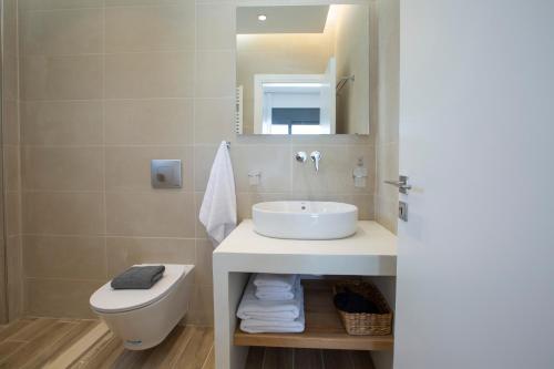 a bathroom with a sink and a toilet and a mirror at Aquamarina Villas in Lefkada Town