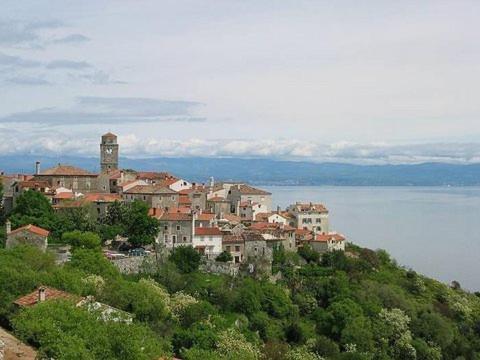 a town on top of a hill next to the water at Apartments Villa Ina in Brseč