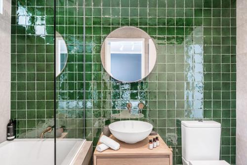 a green tiled bathroom with a sink and a mirror at 3 Salty Sisters in Byron Bay