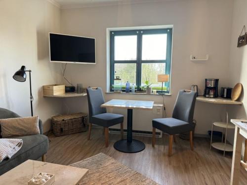 a living room with a table and chairs and a tv at MP 5 Meeresrauschen in Steinbeck