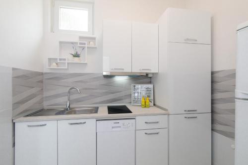 a white kitchen with white cabinets and a sink at Apartment Tara with seaview in Krk