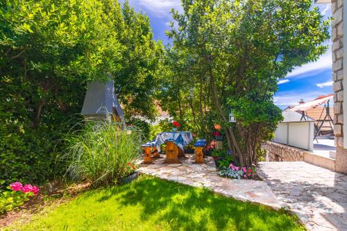 a garden with a table and chairs under a tree at Apartment Tara with seaview in Krk