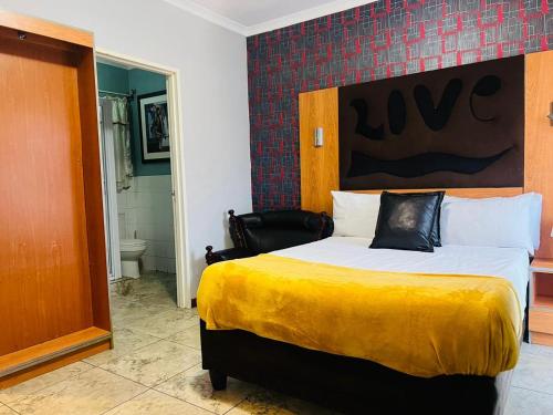 a bedroom with a large bed with a yellow blanket at Parow city -Star Legend Lodge in Cape Town