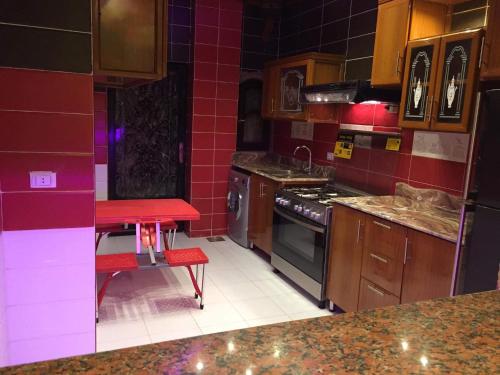 a kitchen with red tile walls and a red stool at الشيخ زايد in Sheikh Zayed
