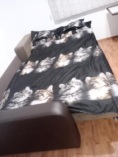 a bed with cats printed on the sheets at Garsoniera Adriana in Băile Herculane