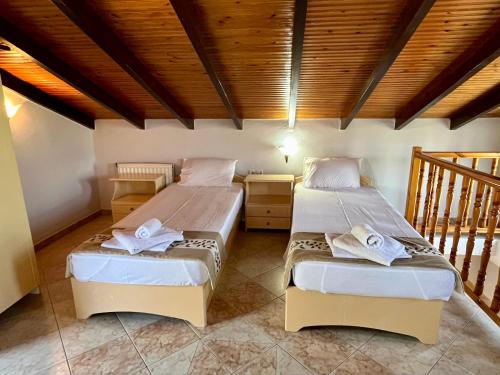 a bedroom with two beds and a wooden ceiling at Oneiro Zois villas in Prinos