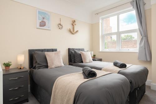 two beds in a bedroom with a window at Large cosy house - free on street parking in Liverpool