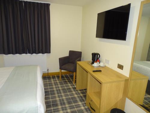 a hotel room with a bed and a desk and a television at Oddfellows Hotel in Carlton