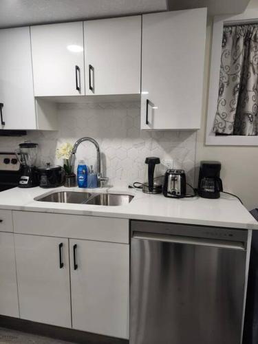 a kitchen with white cabinets and a sink at Modern 2 Bedroom Basement Suite Chappelle Edmonton in Edmonton