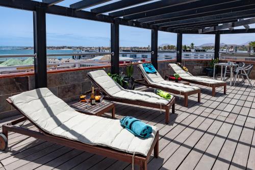 three lounge chairs on a deck with a view of the ocean at Calas Beach Corralejo in Corralejo