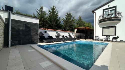 ein Swimmingpool mit Stühlen neben einem Haus in der Unterkunft Family friendly apartments with a swimming pool Pula - 22040 in Pula