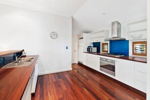 a kitchen with white cabinets and a wooden floor at Caves House Hotel & Apartments Yallingup in Yallingup