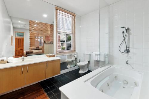 a bathroom with a tub and a toilet and a sink at Caves House Hotel & Apartments Yallingup in Yallingup
