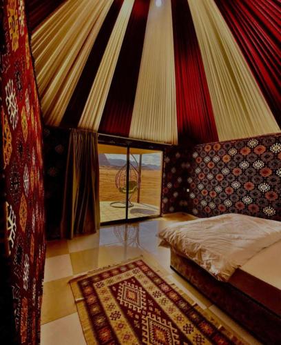 a bedroom with a bed and a window and a rug at Wadi Rum Luxure desert Camp in Wadi Rum