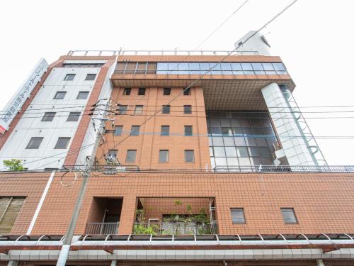 a tall brick building in front of a building at Tabist New World Hotel Kagoshima Kanoya in Kanoya