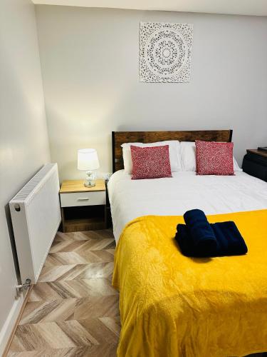 a bedroom with a large bed with a yellow blanket at Comfy Studio Flat and Workspace near Ashton-U-Lyne Station in Stalybridge