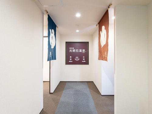 a hallway with white walls and two flags on the wall at Tabist New World Hotel Kagoshima Kanoya in Kanoya