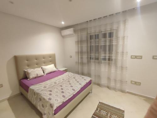 Un dormitorio con una cama con sábanas moradas y una ventana. en Hamamat, en Hammamet Sud