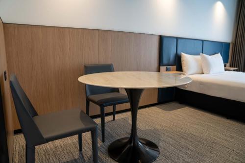 a small room with a table and chairs and a bed at Value Suites Penrith in Penrith