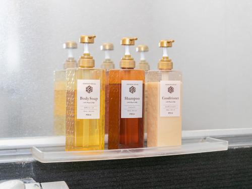 a group of four bottles of soap on a shelf at Tabist New World Hotel Kagoshima Kanoya in Kanoya