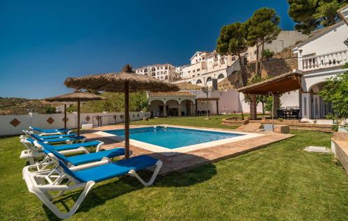 a group of chairs and umbrellas next to a swimming pool at Stunning Home In Casarabonela in Casarabonela