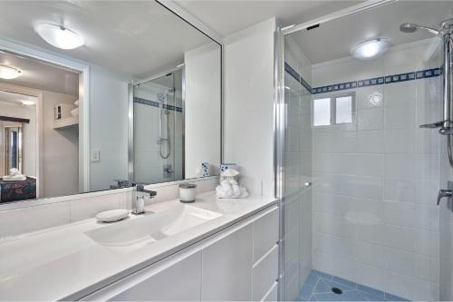 a white bathroom with a sink and a shower at North Cove Waterfront Suites in Cairns
