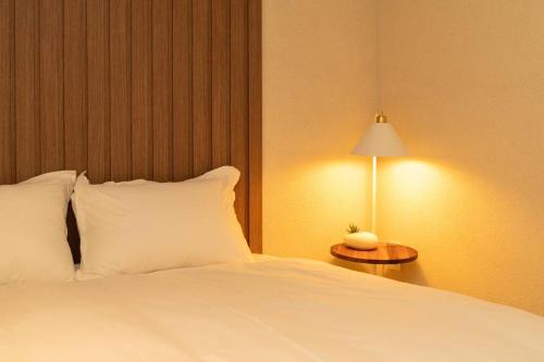 a bed with white pillows and a table with a lamp at The First Gwangan in Busan