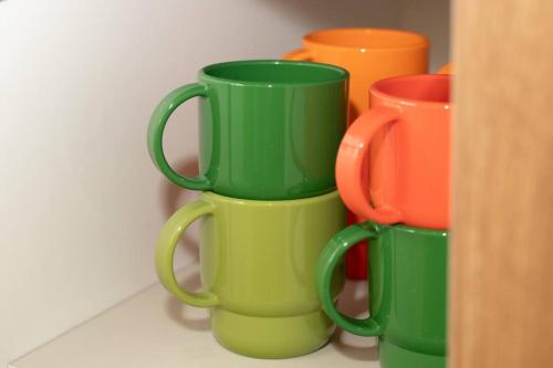 four green coffee mugs are stacked in a shelf at The First Gwangan in Busan